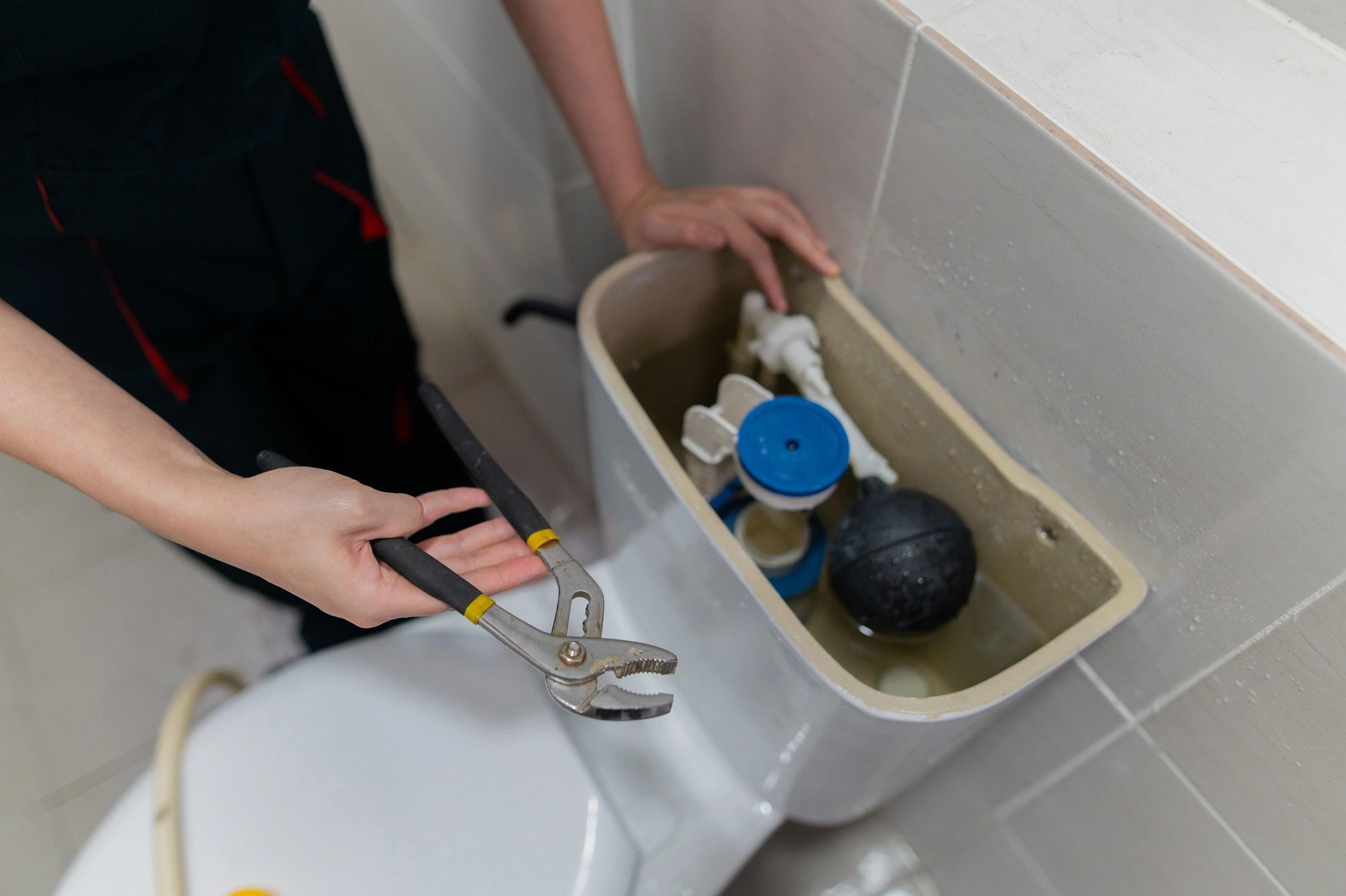 Hand with tools checking and repairing a toilet leak
