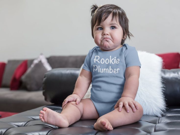 Baby wearing a "Rookie Plumber" bodysuit